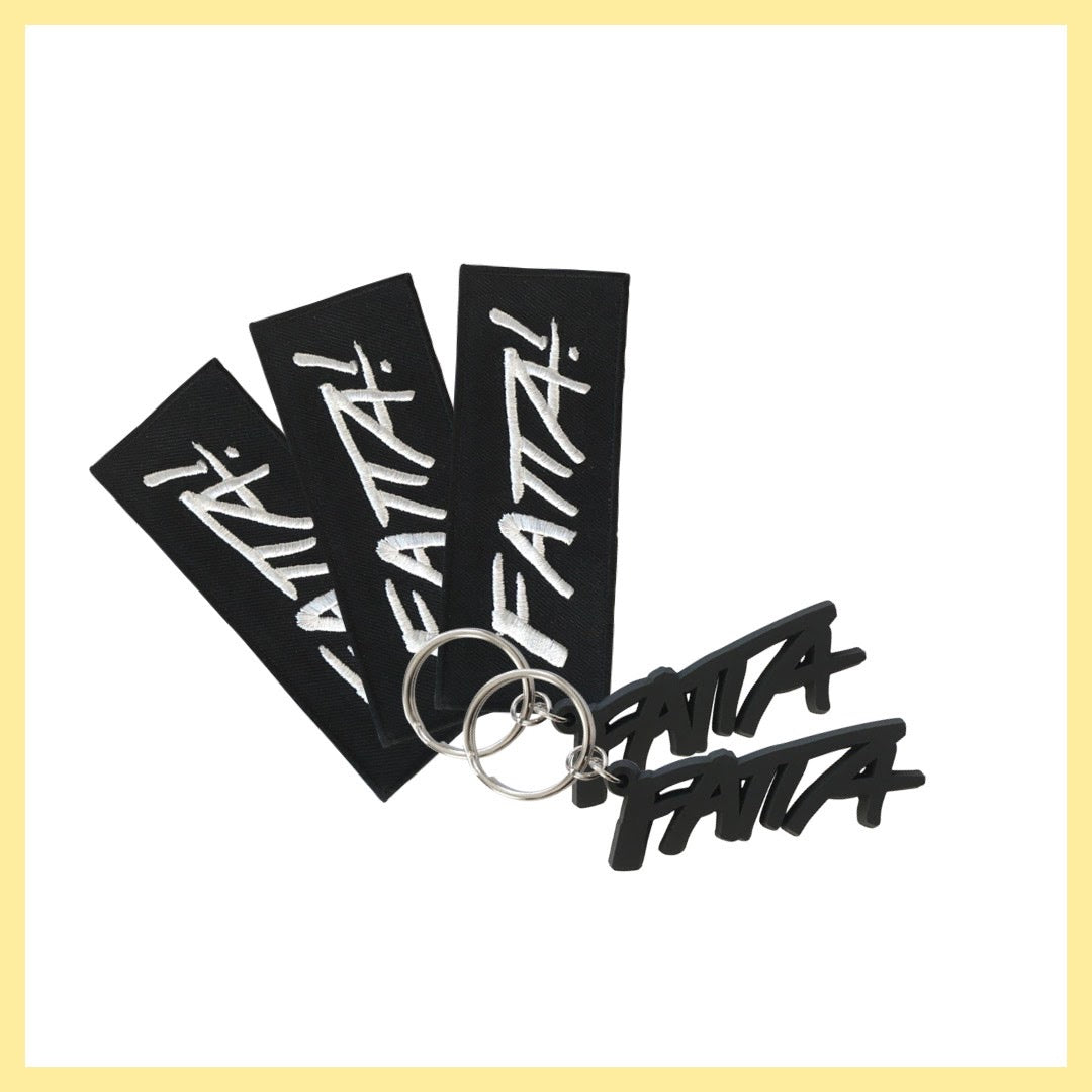 Tre stycken svarta tygmärken med Fatta-loggan i vitt och två stycken nyckelringar med en svart Fatta-logga i mjuk plast. 
