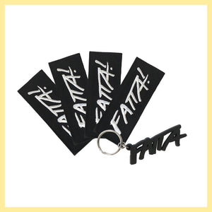 Fyra stycken svarta tygmärken med Fatta-loggan i vitt och en nyckelring med Fatta-loggan i mjuk svart plast. 