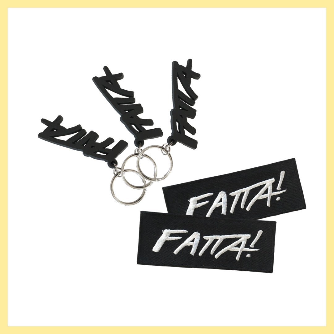 Tre nyckelringar med Fatta-loggan i mjuk svart plast och två svarta tygmärken med Fatta-loggan i vitt.