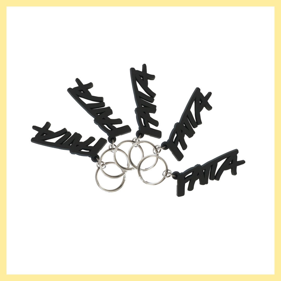 Fyra stycken svarta tygmärken med Fatta-loggan i vitt och en nyckelring med Fatta-loggan i mjuk svart plast. 
